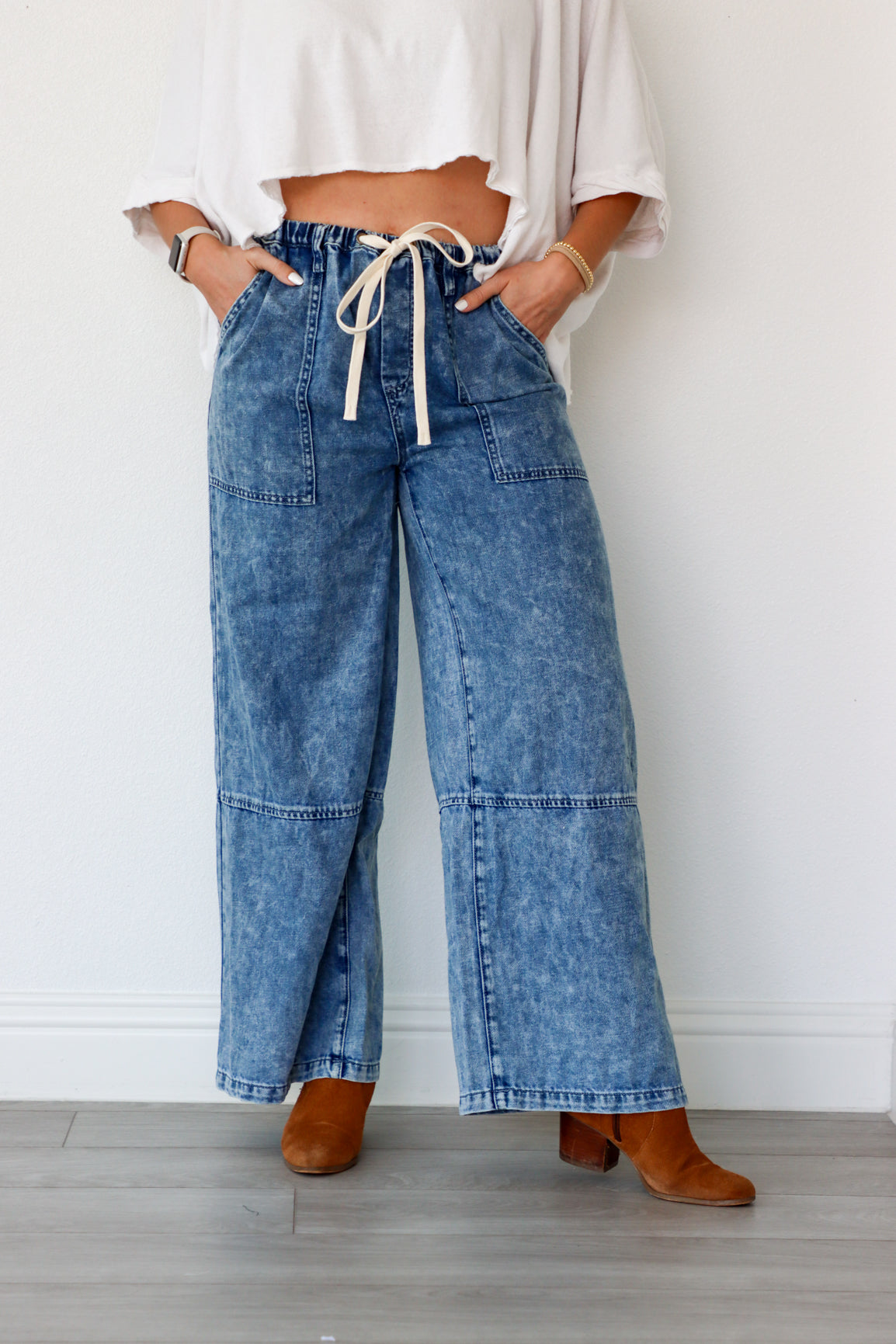 Person wearing blue jeans with a white top against a plain background