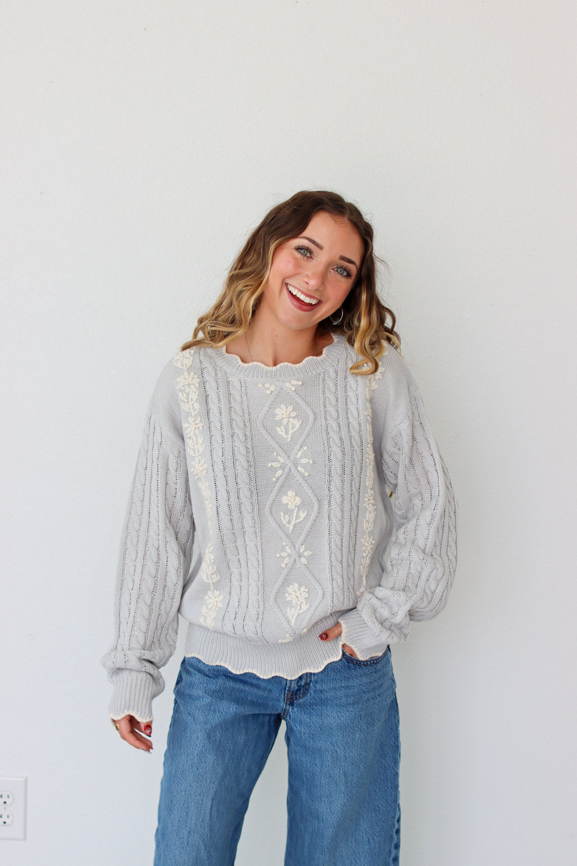 Woman wearing a knit light purple sweater against a white background 