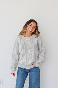 Woman wearing a knit light purple sweater against a white background 