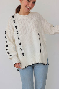 girl wearing white cable knit sweater with black stitch detailing