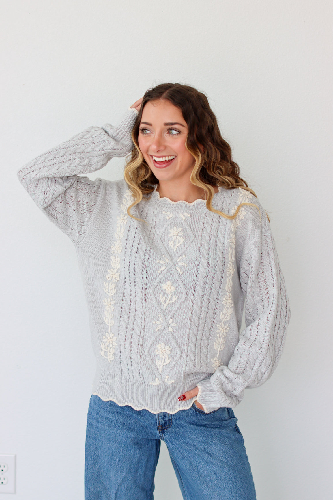 Woman wearing a knit light purple sweater against a white background 