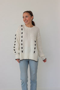 girl wearing white cable knit sweater with black stitch detailing