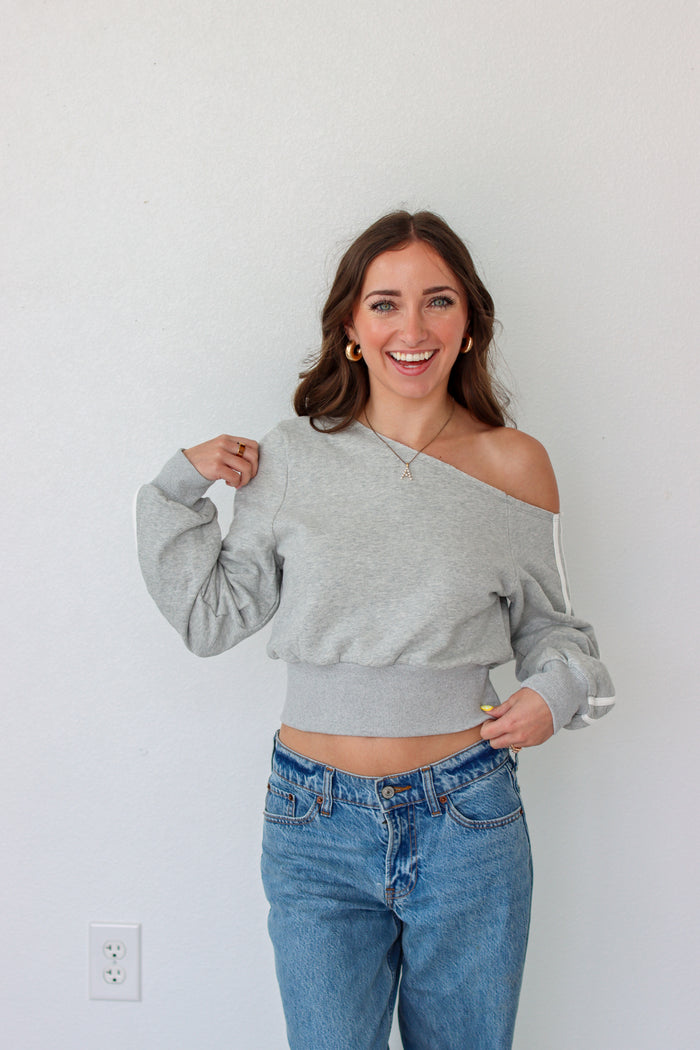 Woman wearing a light gray off the shoulder sweater top 