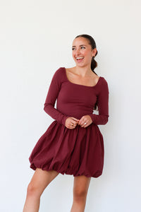 Woman wearing a burgundy dress against a white background
