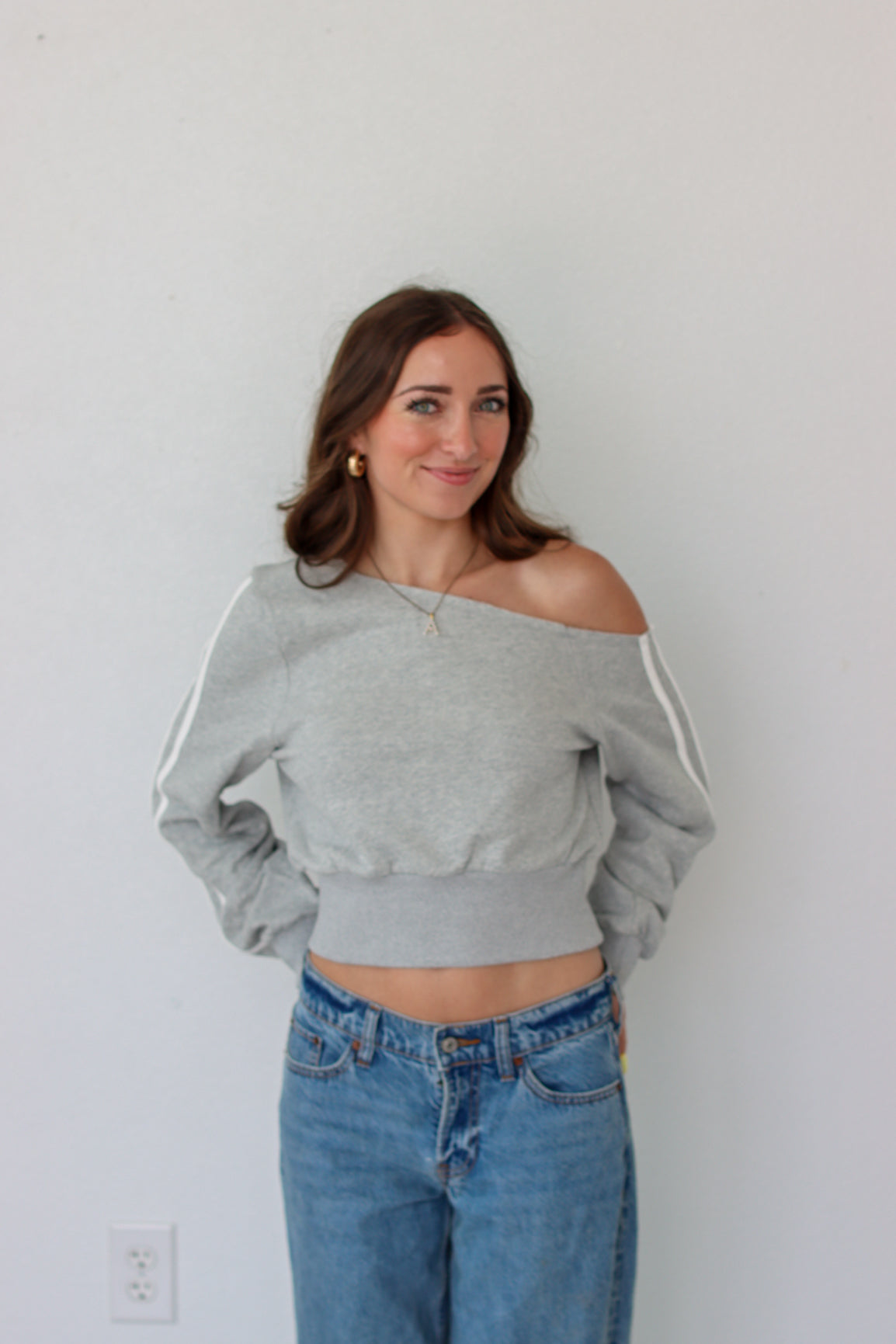 Woman wearing a light gray off the shoulder sweater top 