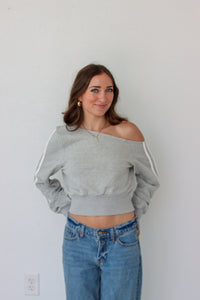 Woman wearing a light gray off the shoulder sweater top 