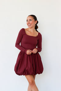 Woman wearing a burgundy dress against a white background