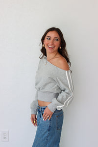 Woman wearing a light gray off the shoulder sweater top 