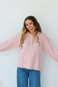 Woman wearing a light pink checkered quarter button up sweater