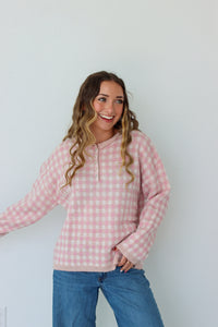 Woman wearing a light pink checkered quarter button up sweater