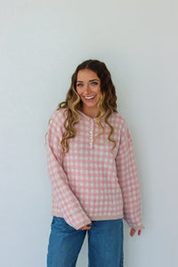 Woman wearing a light pink checkered quarter button up sweater