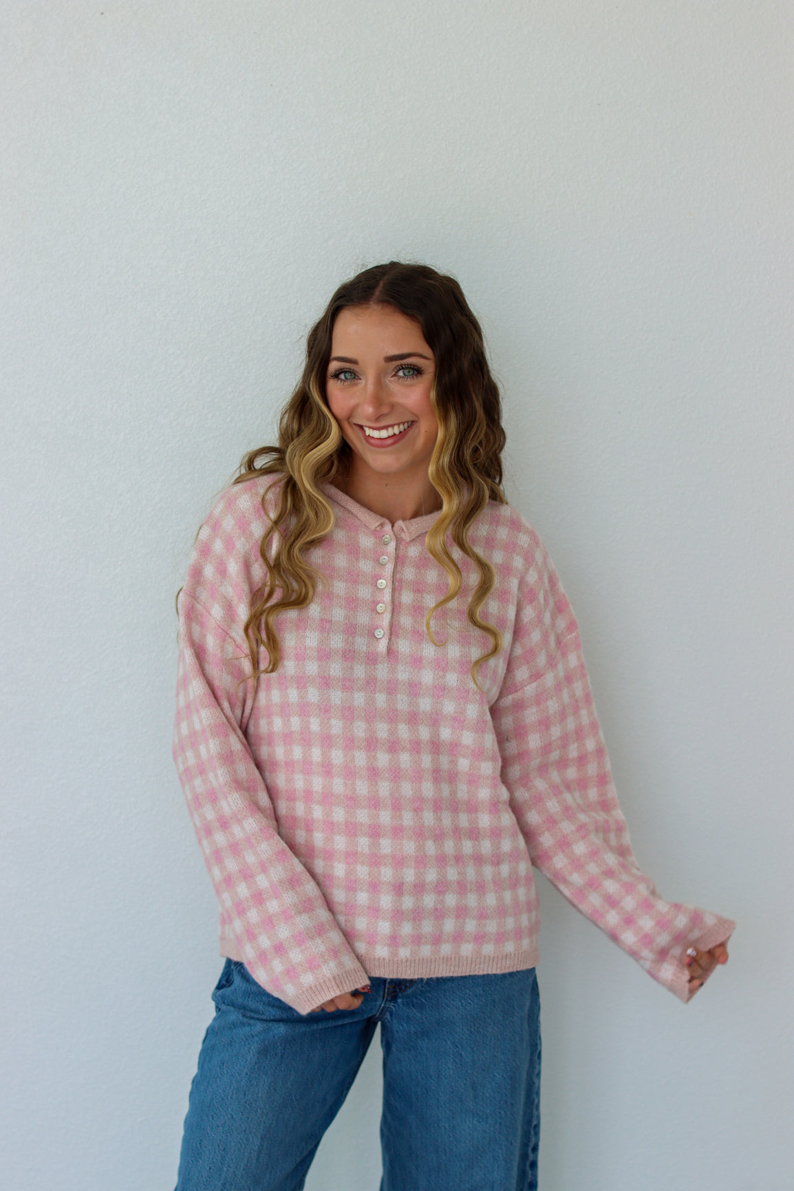 Woman wearing a light pink checkered quarter button up sweater