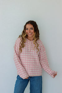 Woman wearing a light pink checkered quarter button up sweater