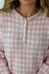 Close up of light pink checkered button up sweater 