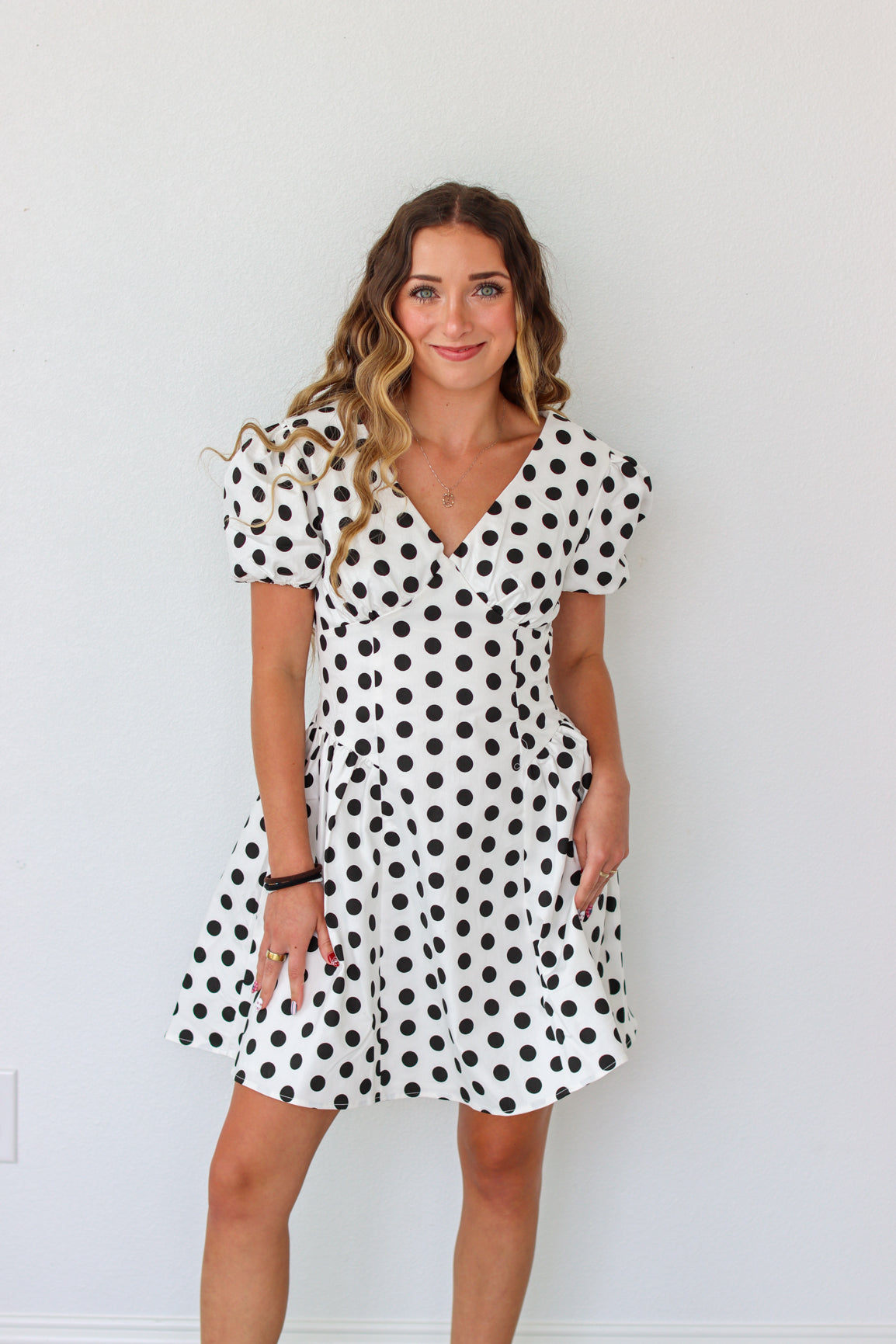Woman wearing a black and white polka dot dress against a plain background