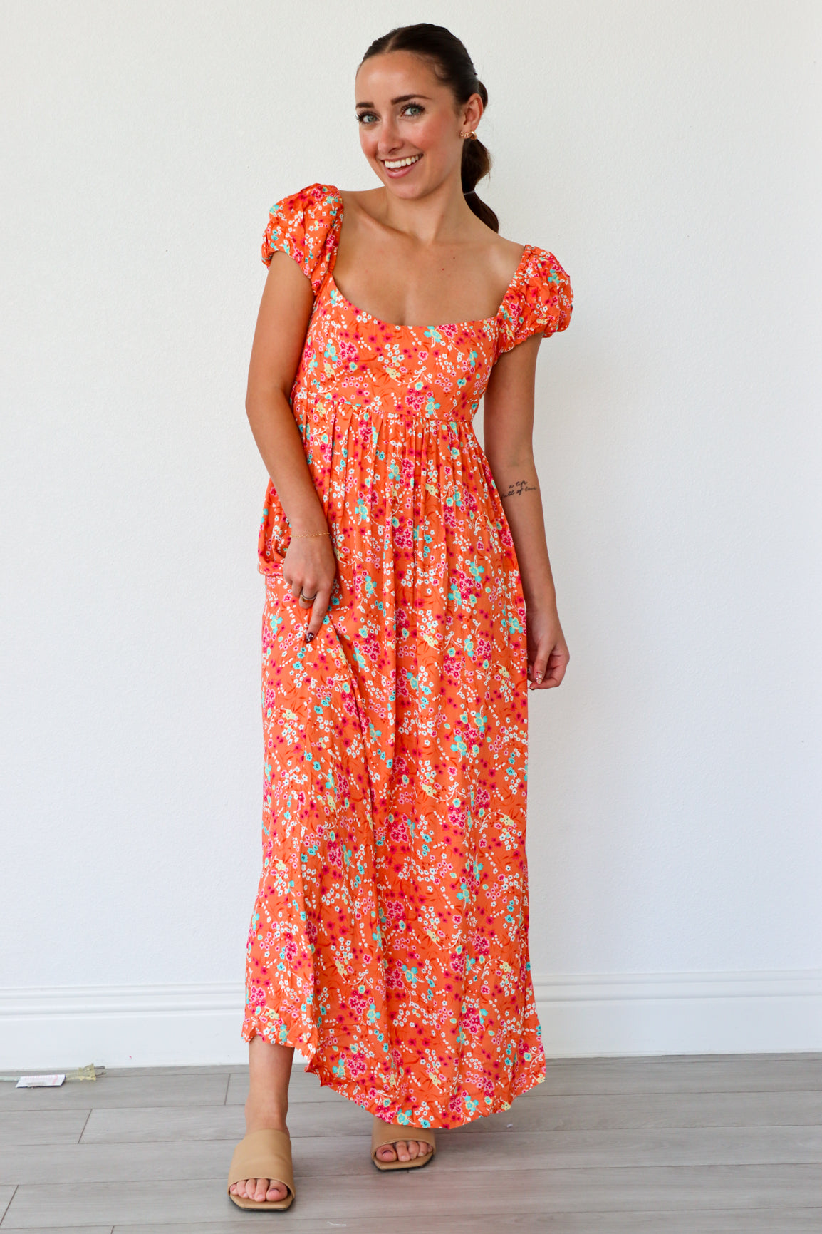 Woman wearing a floral dress against a white wall