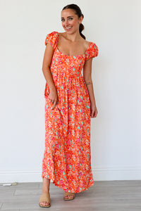 Woman wearing a floral dress against a white wall