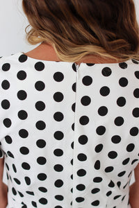 Close-up of a person wearing a black and white polka dot dress.