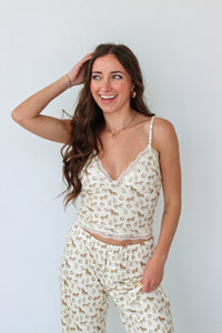 Woman wearing a cream lace top with western motifs with matching pants against a light background
