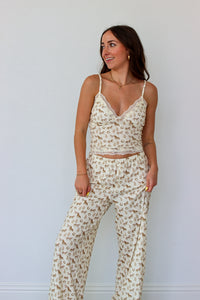 Woman wearing a cream lace top with western motifs with matching pants against a light background