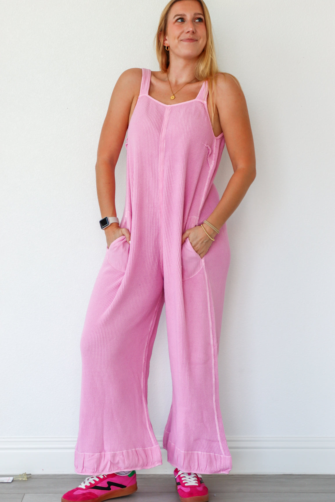 Woman wearing a pink jumpsuit against a white background