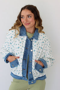 Woman wearing a floral denim jacket with a white background