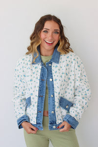 Woman wearing a floral denim jacket with a white background