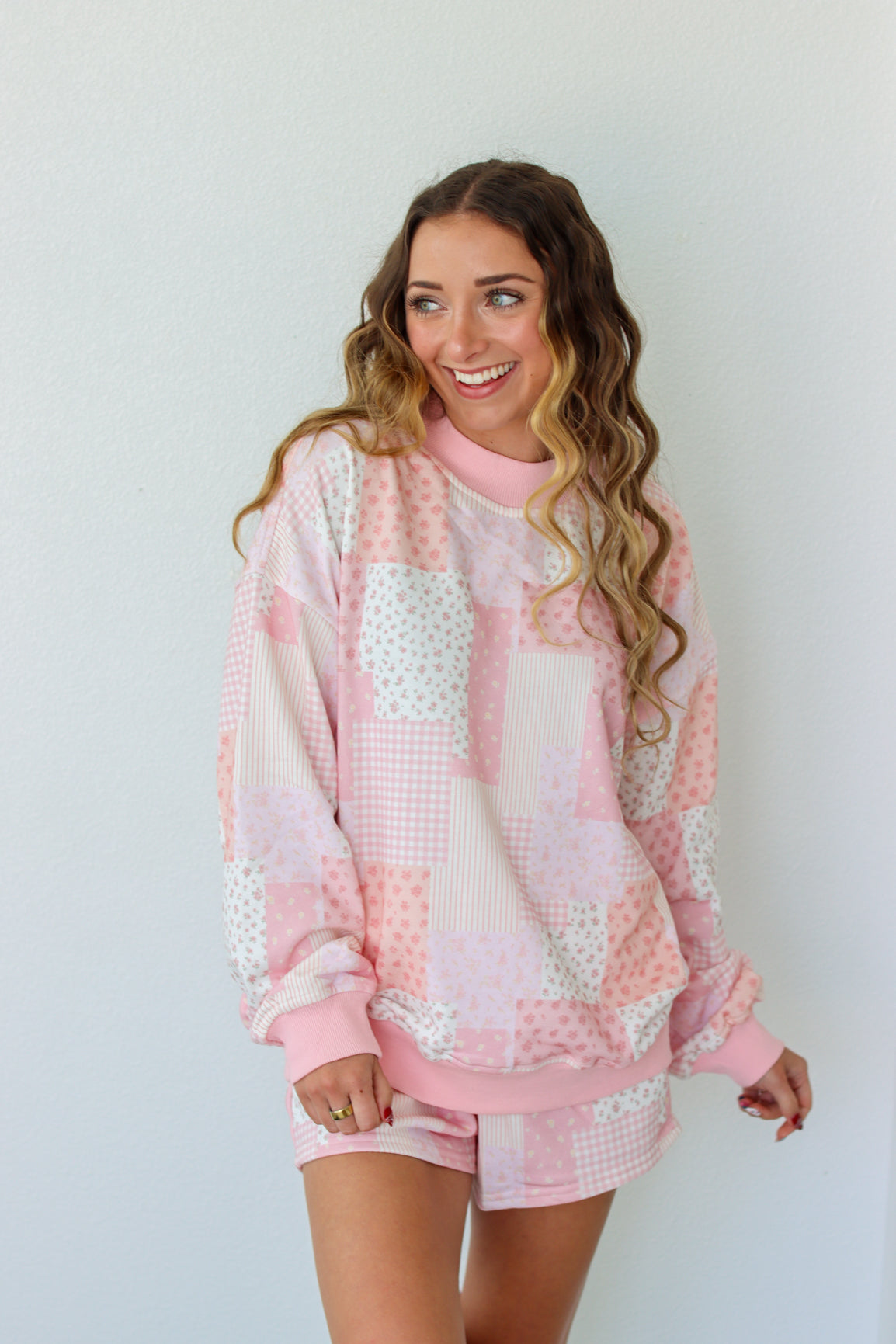 Woman wearing a pink and white outfit against a plain background