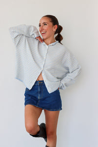 Woman wearing a striped sweater and denim skirt against a plain background