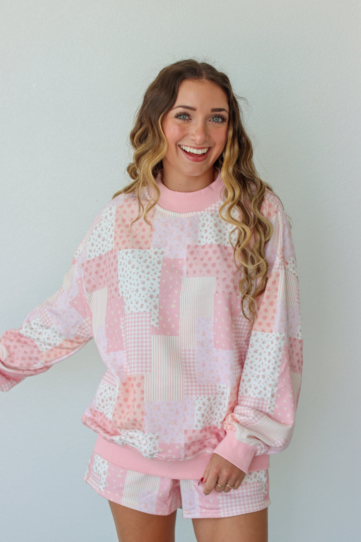 Woman wearing a pink and white outfit against a plain background