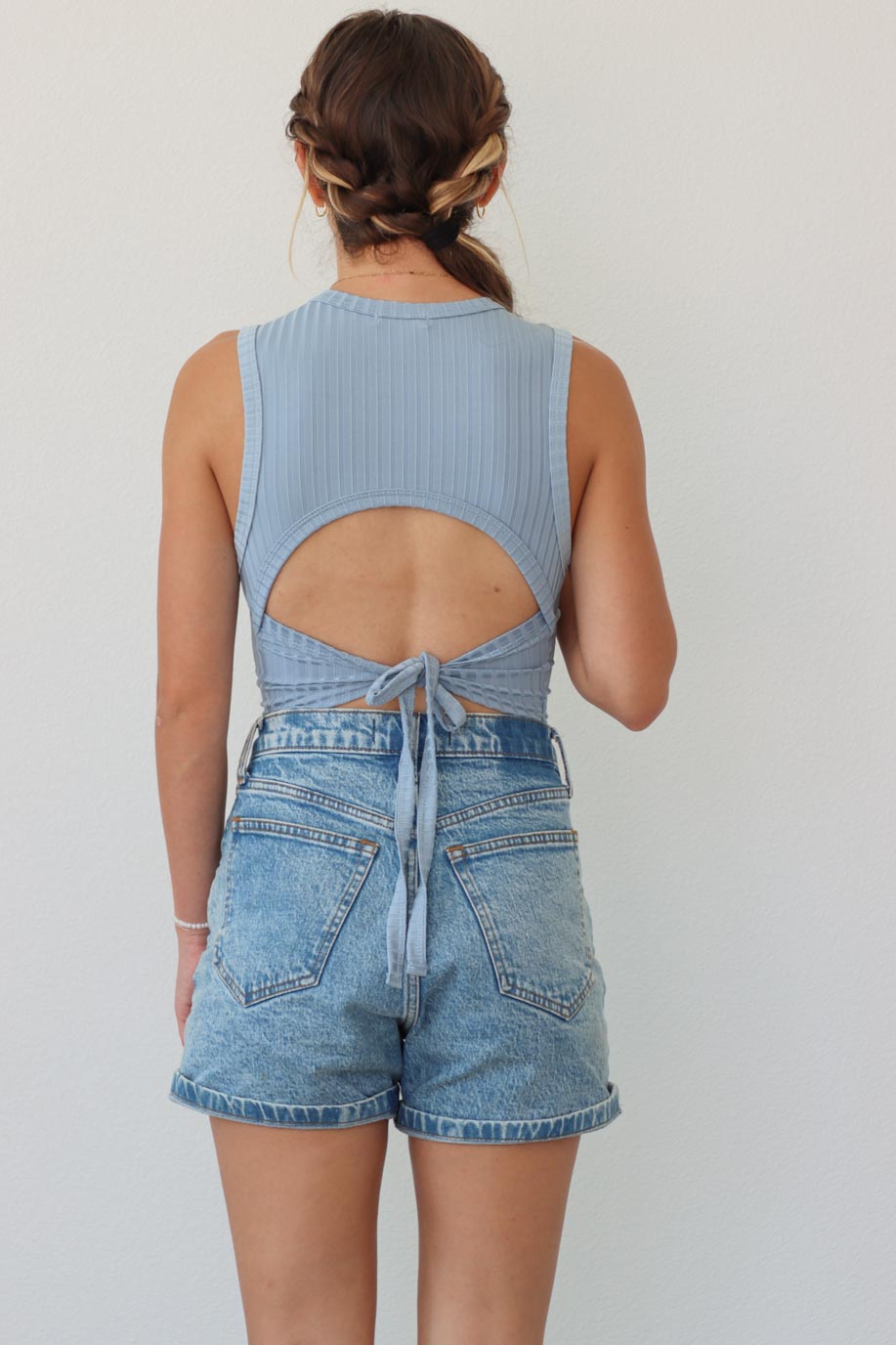 girl wearing light blue tank top with open back detailing