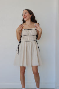 girl wearing cream short dress with black trim detailing