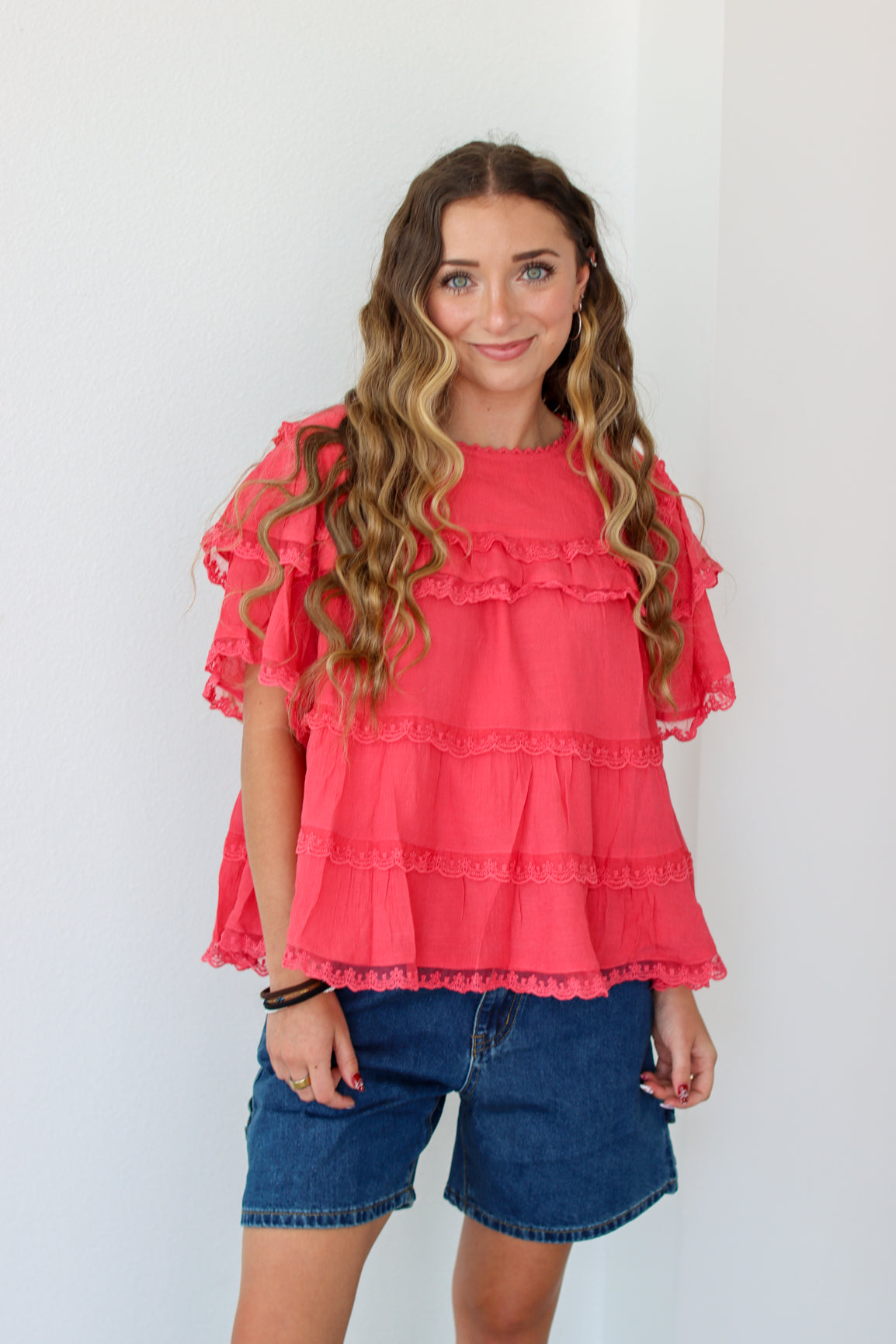 Woman wearing a ruffled top and denim shorts against a white background