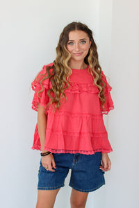 Woman wearing a ruffled top and denim shorts against a white background