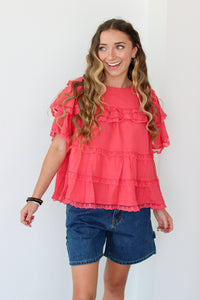 Woman wearing a ruffled top and denim shorts against a white background