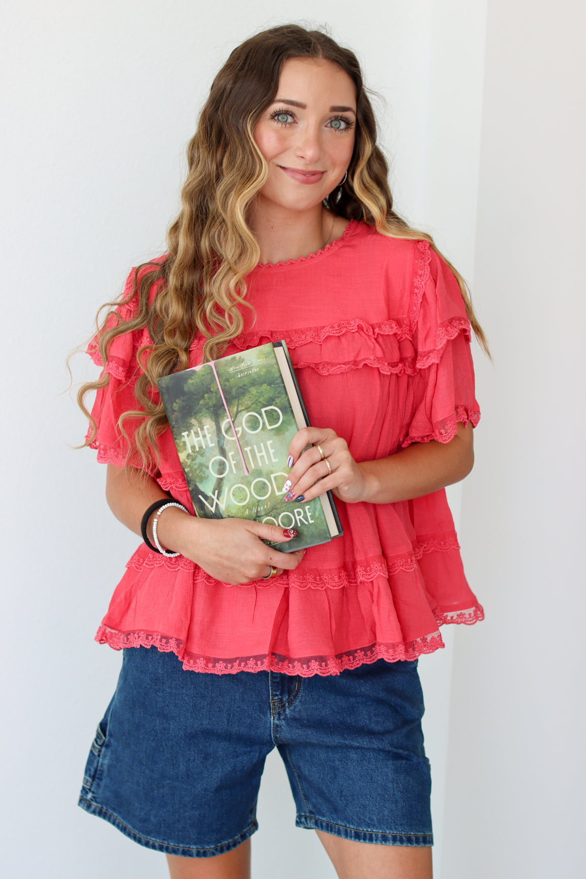 Woman wearing a ruffled top and denim shorts against a white background