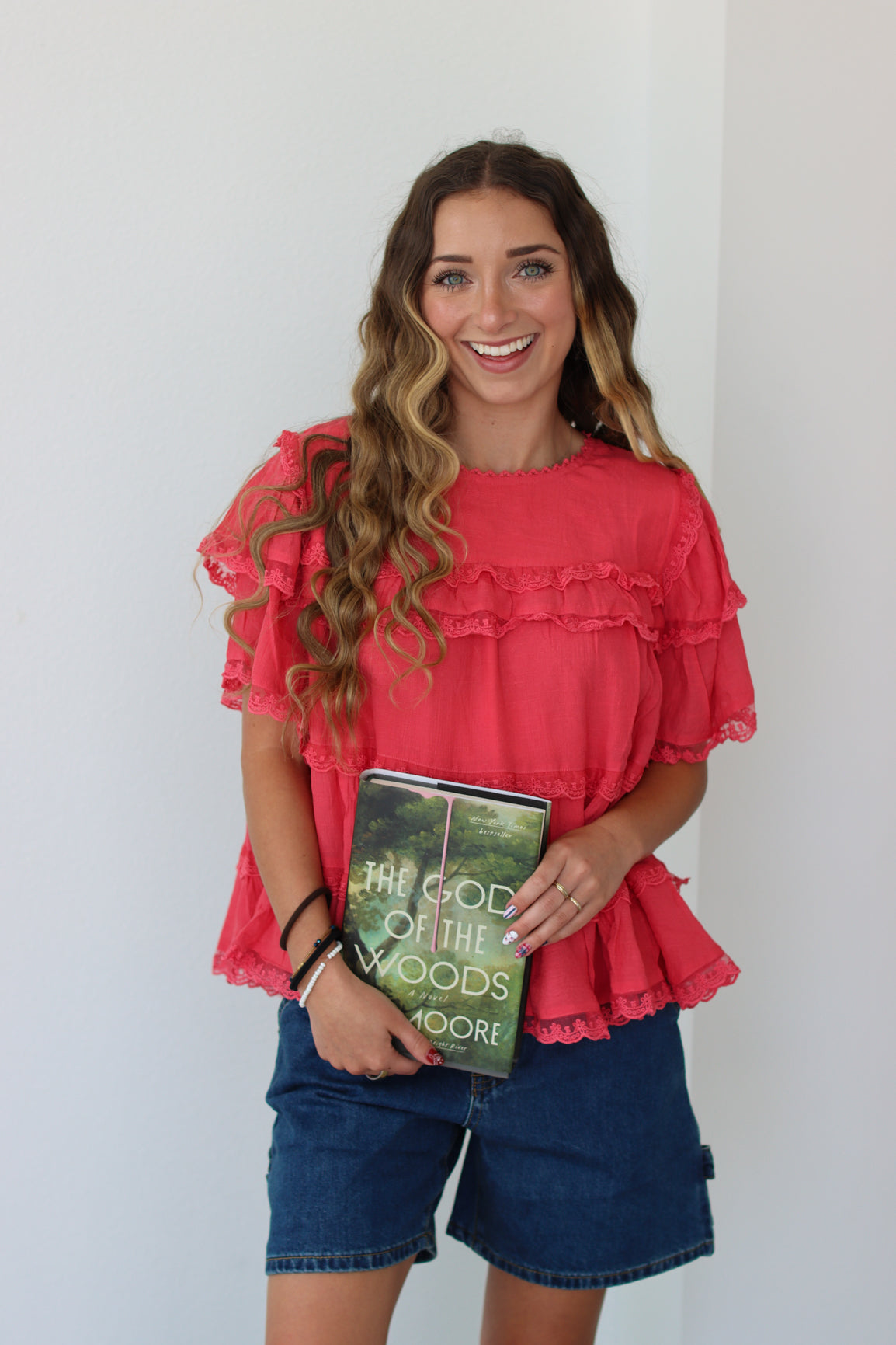 Woman wearing a coral ruffled top against a white background