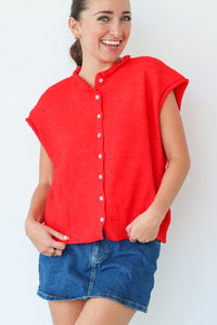 Woman wearing a red sleeveless top and denim shorts against a white background
