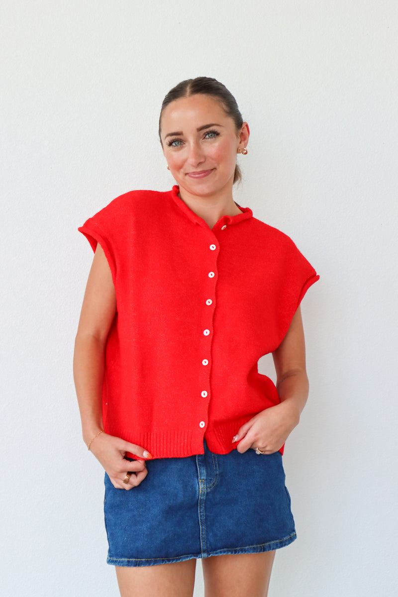 Woman wearing a red sleeveless shirt and blue denim skirt against a white background
