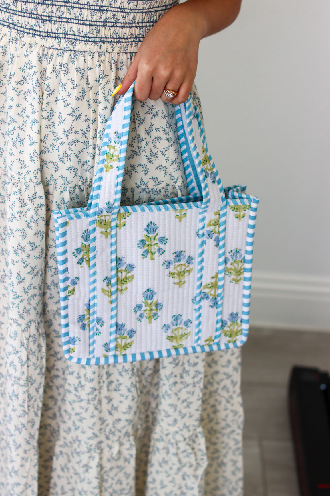 Person holding a small floral-patterned bag with blue accents