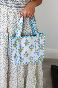 Person holding a small floral-patterned bag with blue accents