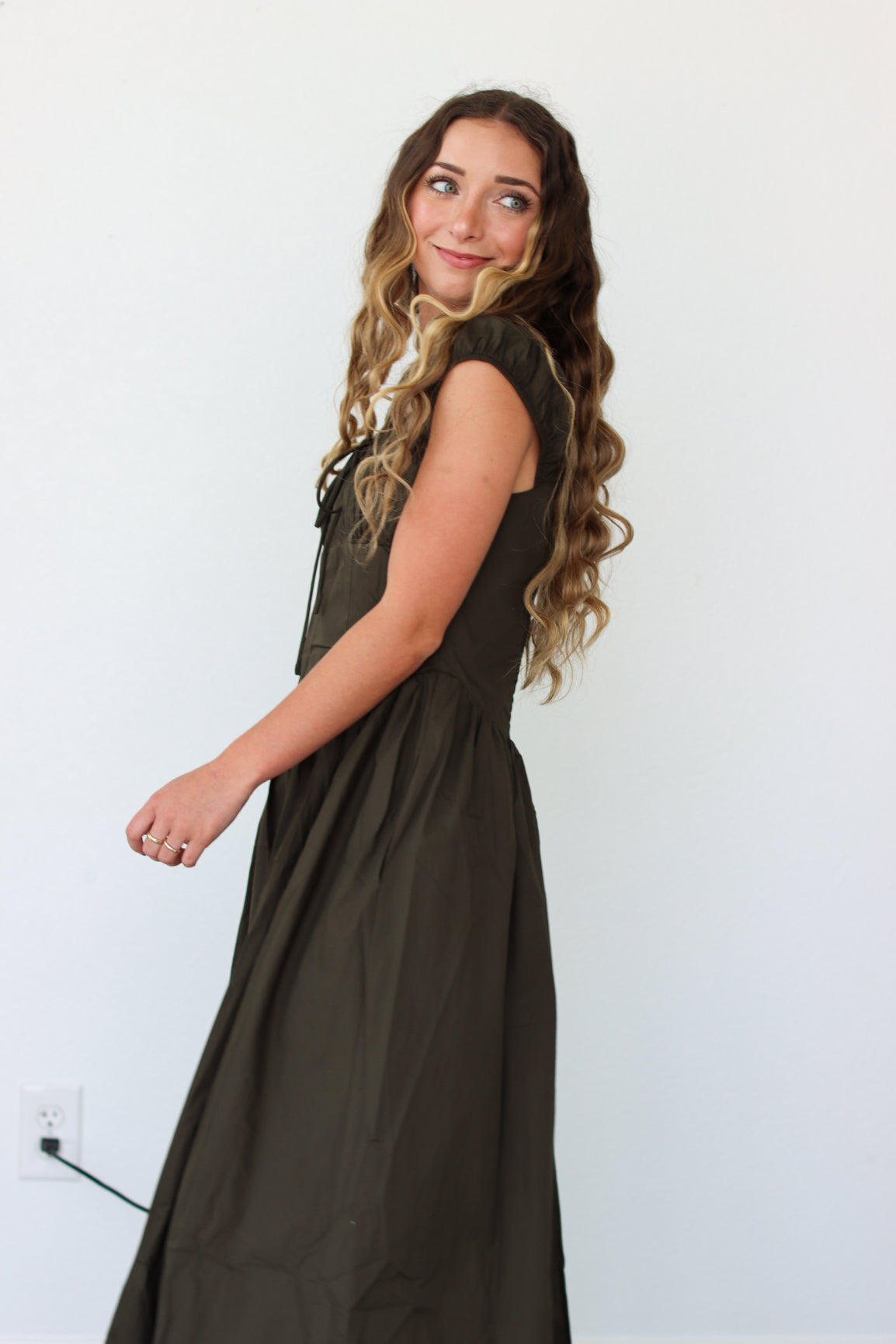 Woman wearing a dark green maxi dress against a white background 