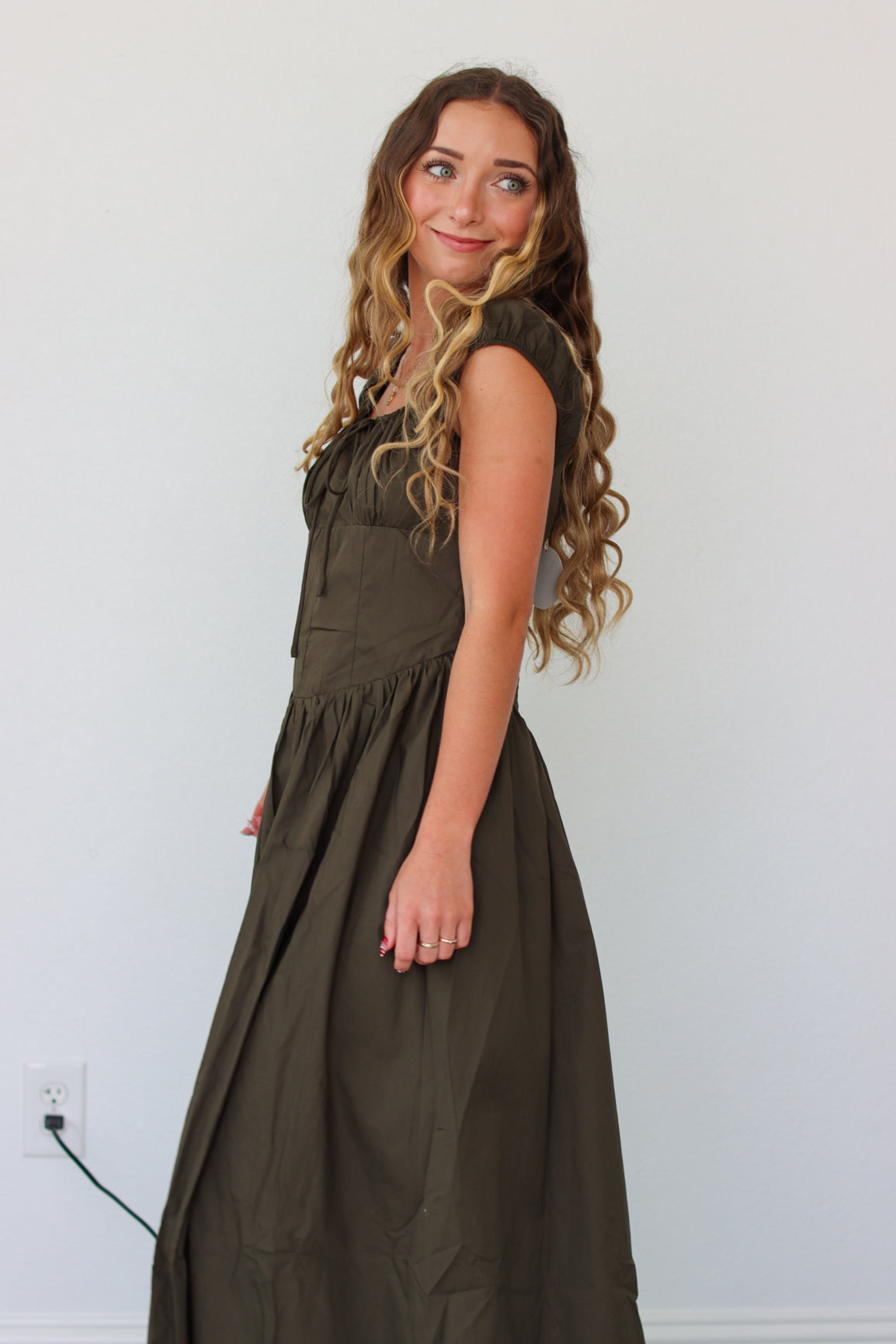 Woman wearing a dark green maxi dress against a white background 