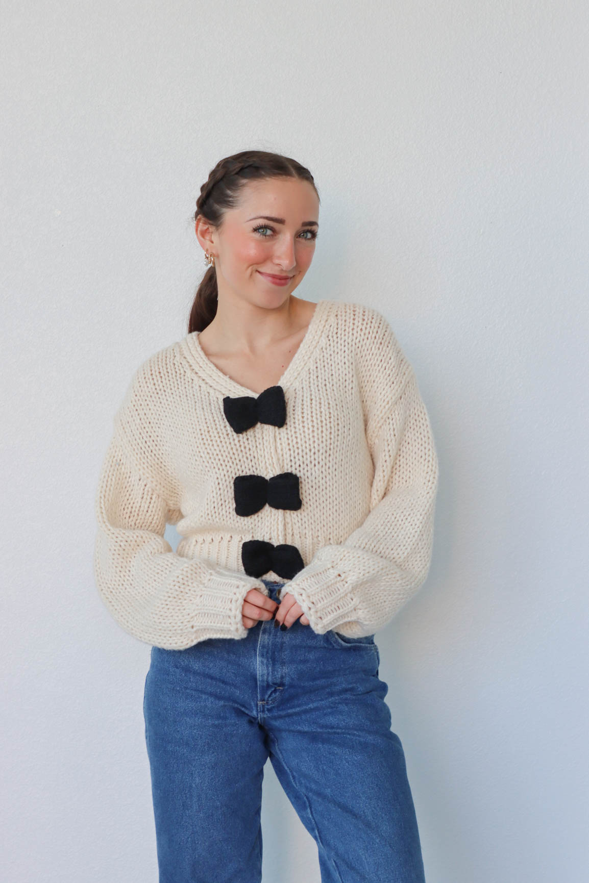 girl wearing cream knit sweater with black bow detailing