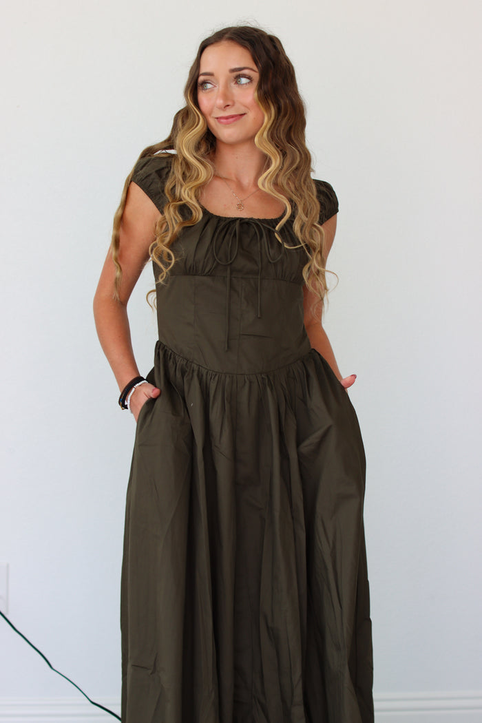 Woman wearing a dark green maxi dress against a white background 