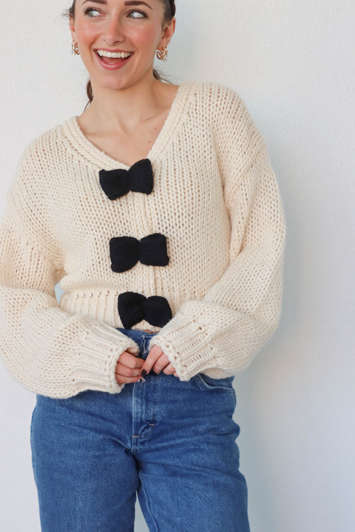 girl wearing cream knit sweater with black bow detailing