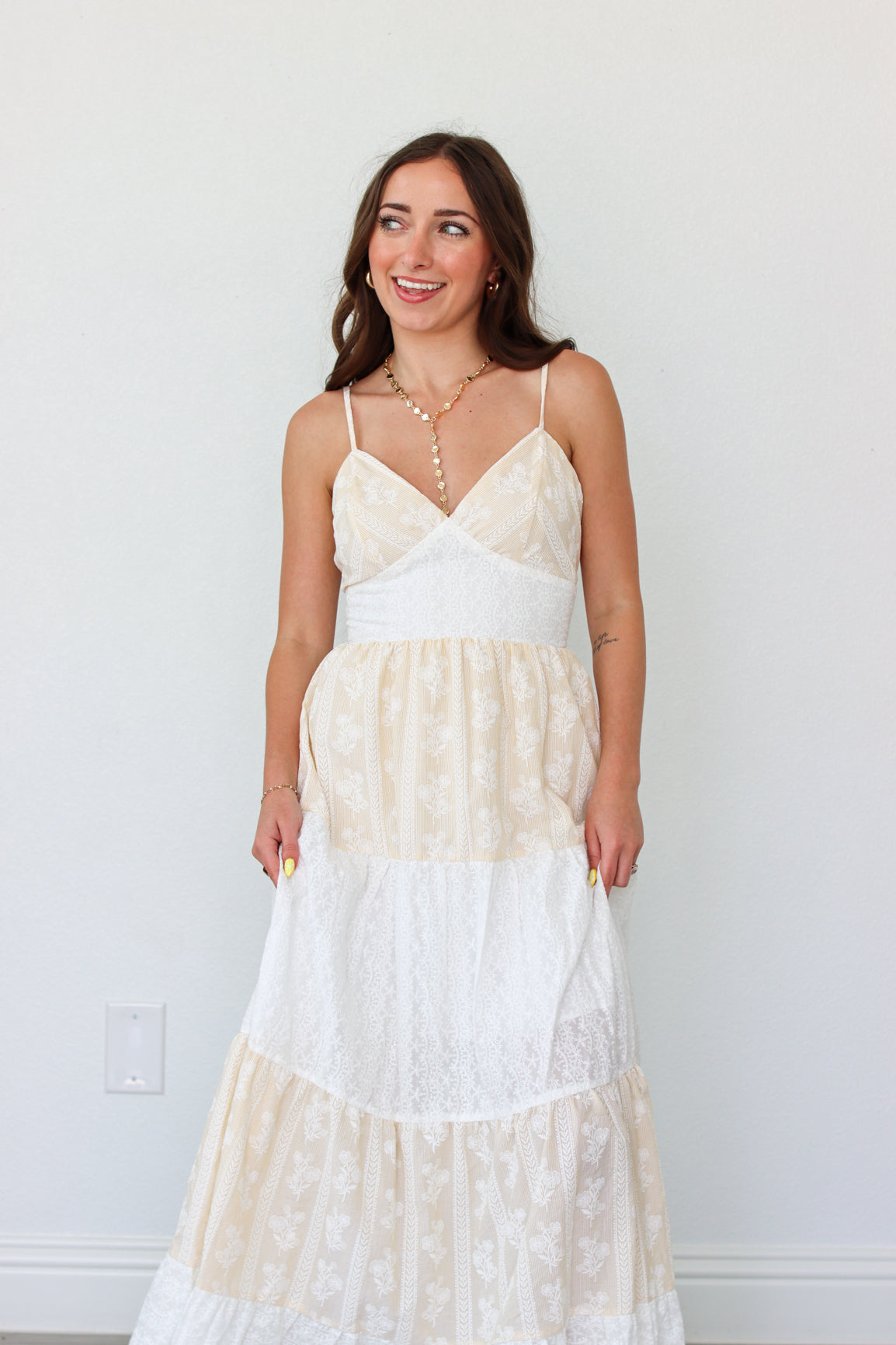 Woman wearing a white tiered maxi dress against a white background 