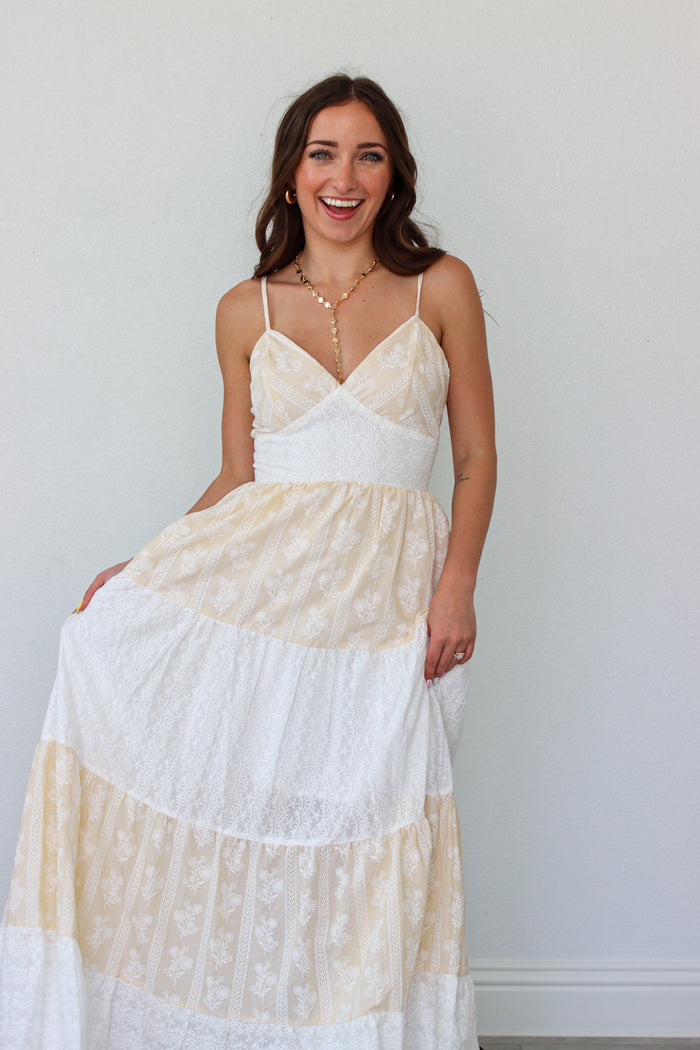 Woman wearing a white tiered maxi dress against a white background 
