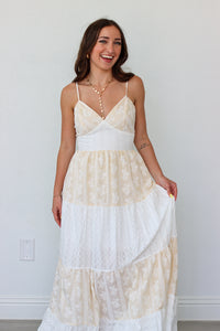 Woman wearing a white tiered maxi dress against a white background 