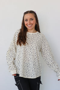 girl wearing cream long sleeve top with floral pattern